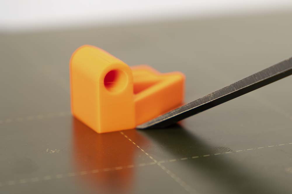 Detailaufnahme des Ablösen eines 3D Druck Bauteils von der Druckplatte mittels Stechbeitel 