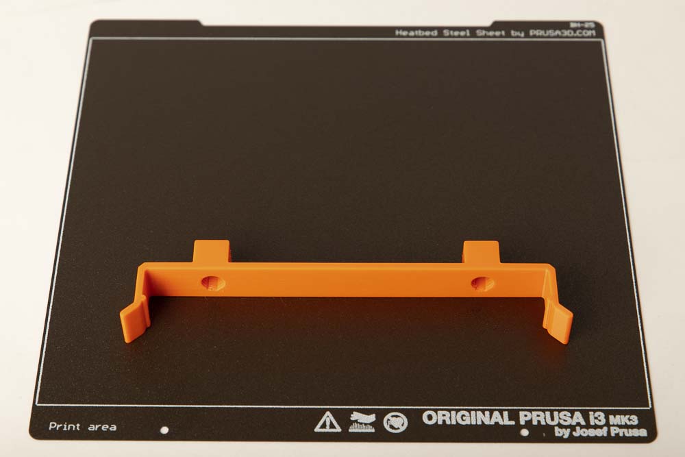 3D gedruckte Befestigungsklammer H12 auf einer Druckplatte eines 3D Druckers in orangen PETG Filament gedruckt