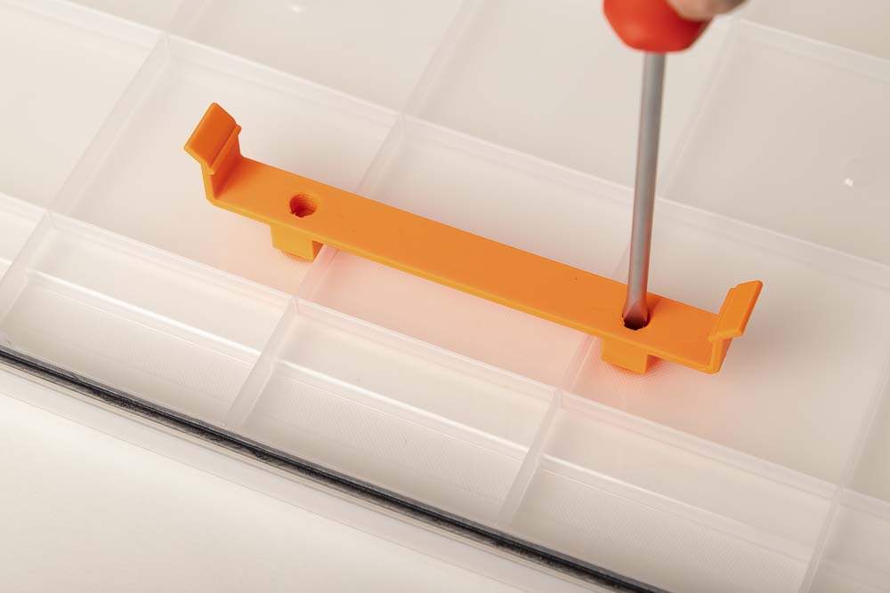 Die 3D gedruckte Befestigungsklammer H12 für die Trockenmittelbox wird am Deckel der Iris 50l Box mittels Schlitzschraubenzieher befestigt.
