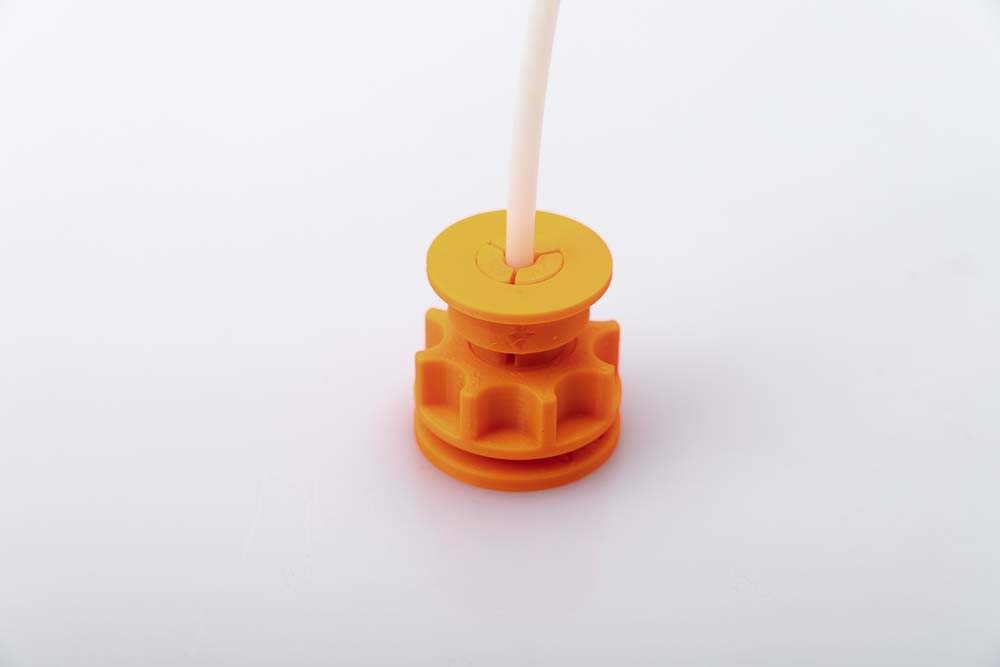 Fertig zusammengebaute 3D gedruckte Fialment Durchführung zum Test der richtigen Modelle. Bestehend aus Durchführung, Mutter, Klemmring und einem PTFE Schlauchstück. Alle Teile sind in orangen PETG Filament mit einer Schichthöhe von 0,2 mm gedruckt worden.