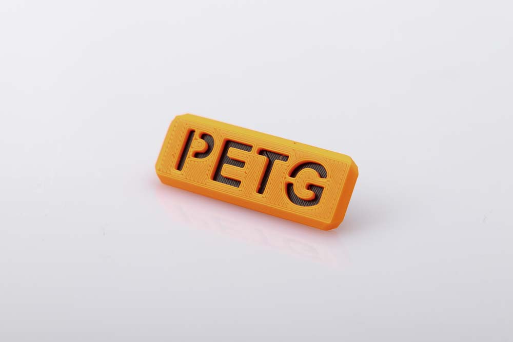 Material Schild von Orangen PETG Filament mit schwarzer Kontrastplatte.