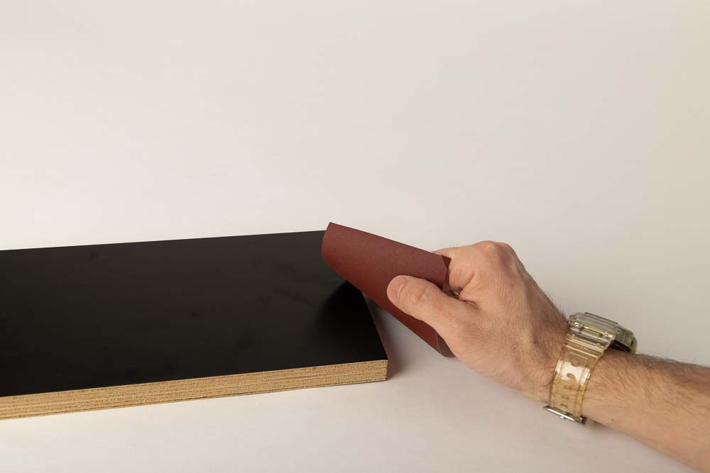 Die Schnittkanten der Basisplatte der Halterung für Filament Box werden mit Schleifpapier abgezogen.