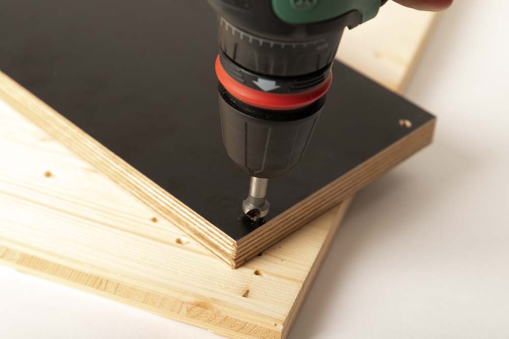 Senken der 4 mm Durchgangsbohrungen auf der Basisplatte der Filament Box Halterung. Unter der Platte ist ein Stück Opferholz damit der Tisch nicht beschädigt wird.