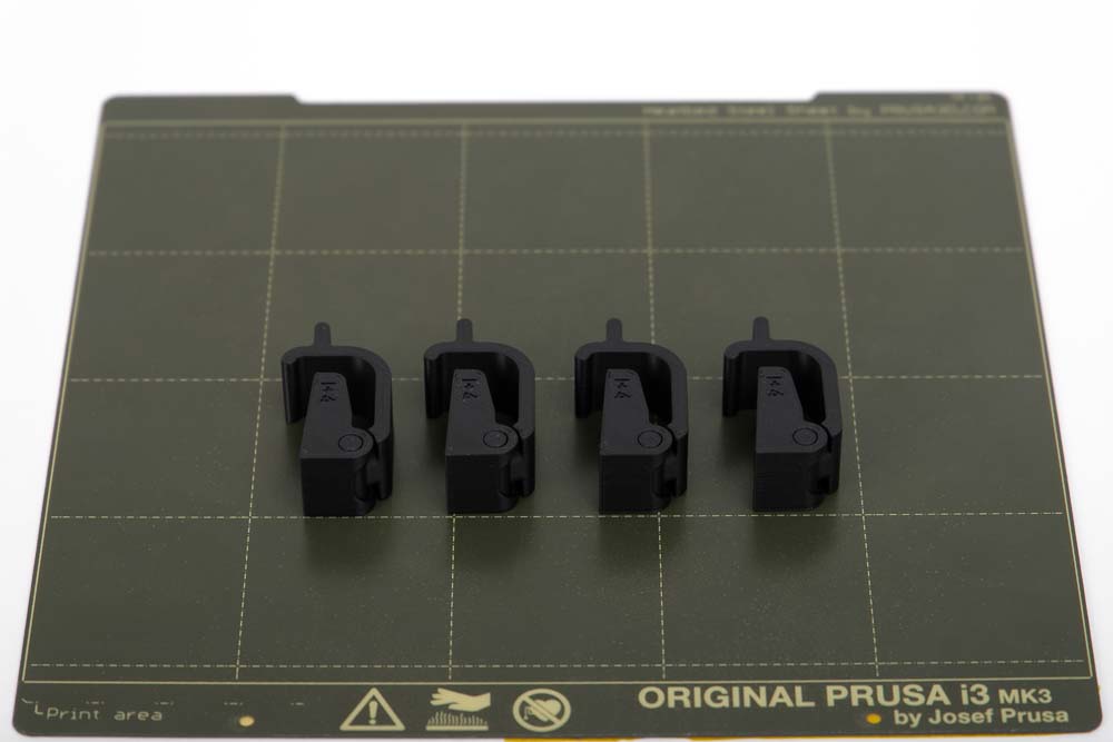 Druckplatte des Prusa i3 MK3S mit 4 Stück 3D gedruckten Verschlüssen für Samla Boxen 22l in schwarzen PETG Filament.