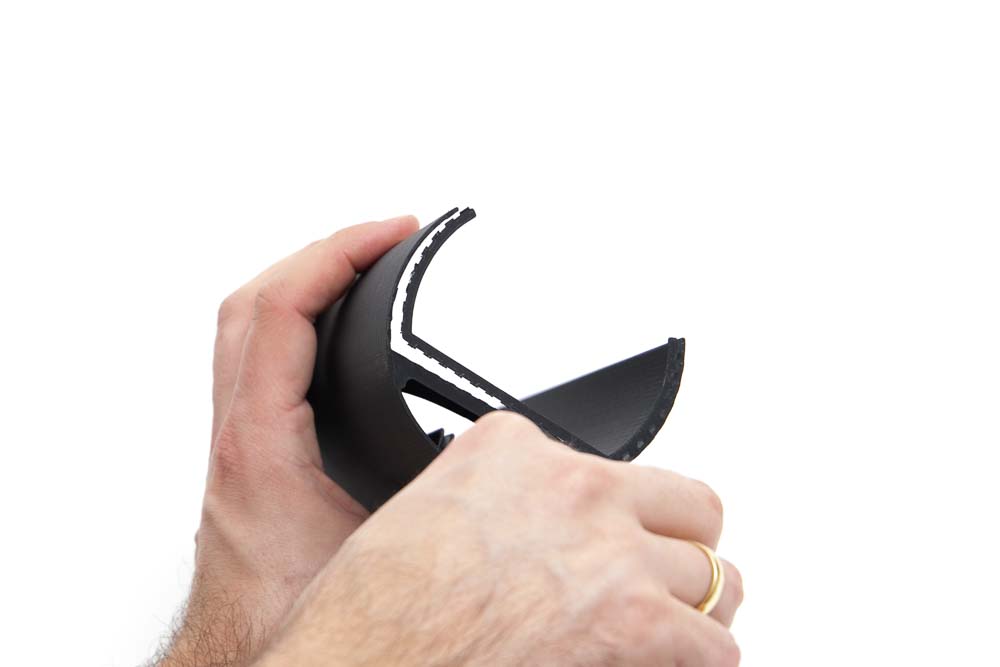 Support structures of a 3D printed inner part of the 3D printed pendant light are removed with a utility knife. A good portion of the support structure has already been cut off.