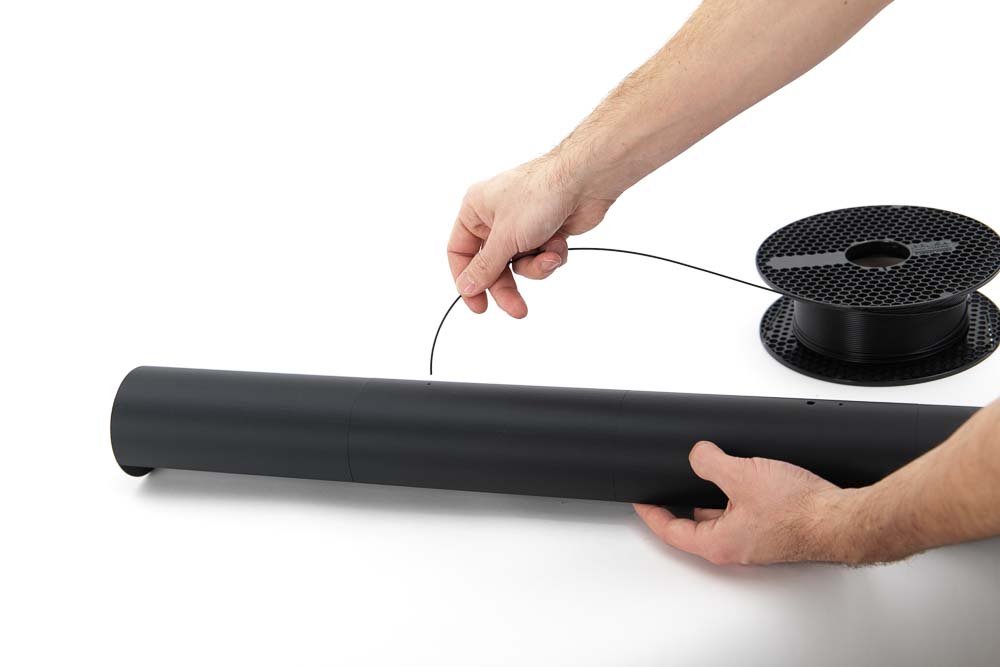 Filament is threaded into the 3D printed light fixture to later serve as a suspension cord