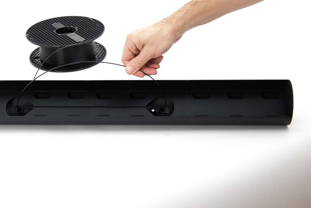 Filament is threaded through the second hole in the 3D printed light body to later serve as a suspension cord