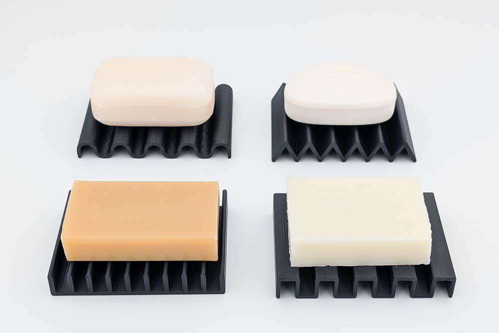 3D Druck Seifenablage mit verschiedenen Seifen, gedruckt in matt schwarzen Filament, zeigt die vier verschiedenen Designs: Rippen Rechteck, Dreieck und Wellen.